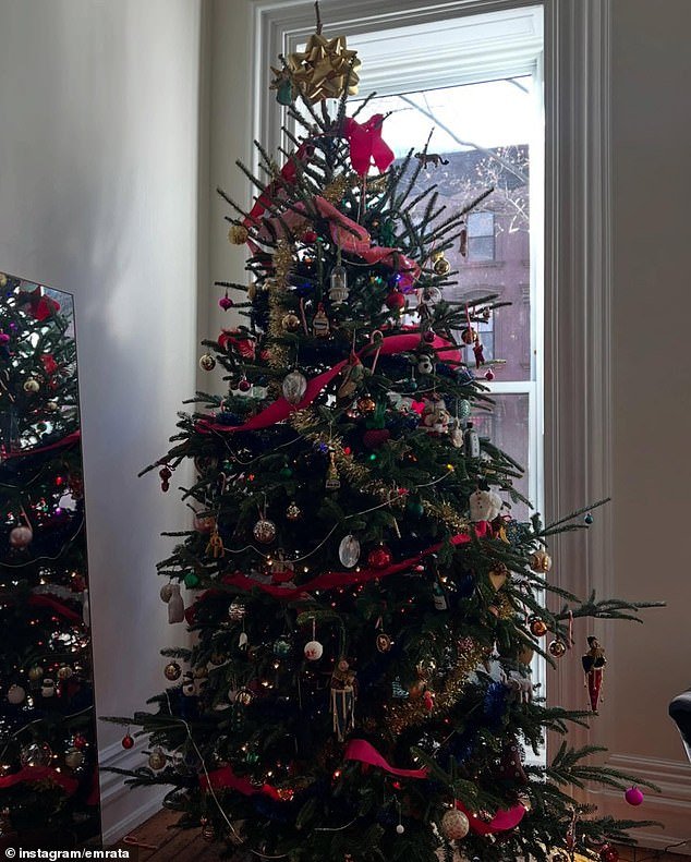 Ratajkowski could be seen climbing a ladder to add decorations to the upper portion of the tree - which included colorful lights and red ribbon