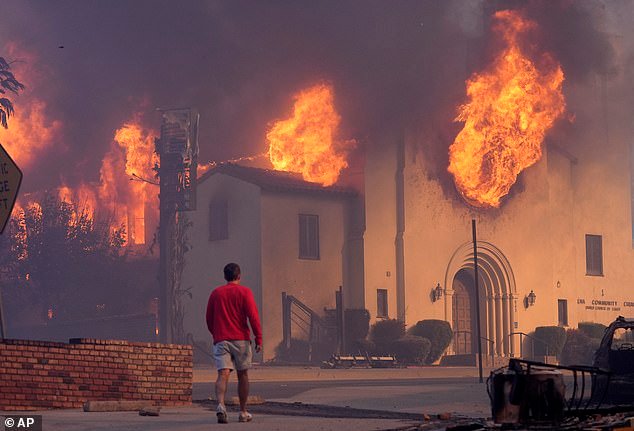 A man walks in front of the burning Altadena Community Church, Wednesday, Jan. 8, 2025, in in Pasadena, Calif