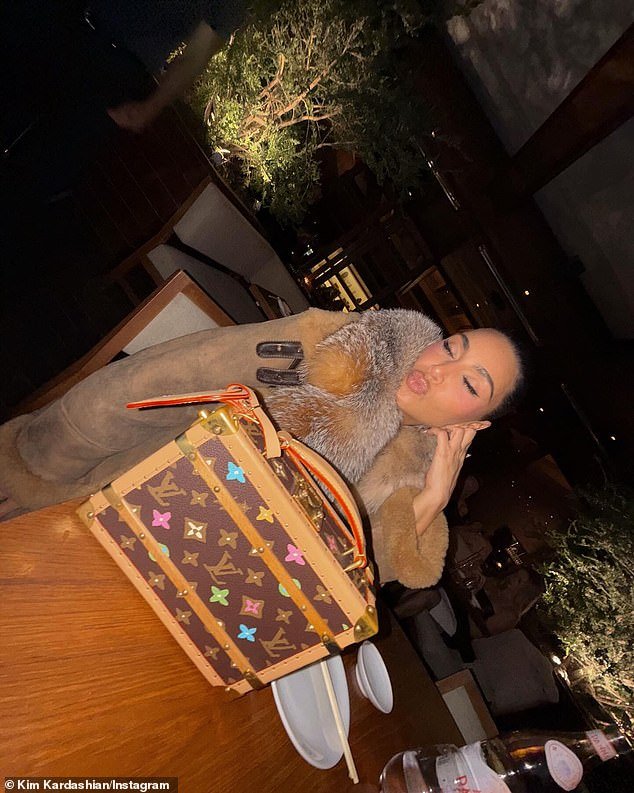 Kim puckered her lips at the table with her expensive Louis Vuitton box bag resting prominently in the foreground