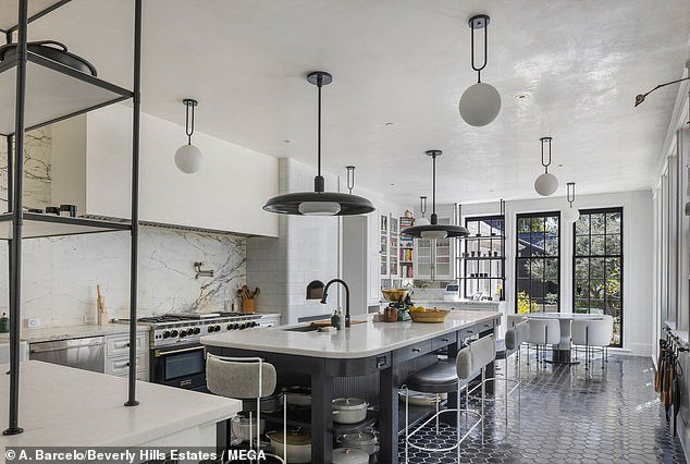 The kitchen is every chef's dream, featuring high ceilings, floor-to-ceiling windows, black tile floors and a massive island