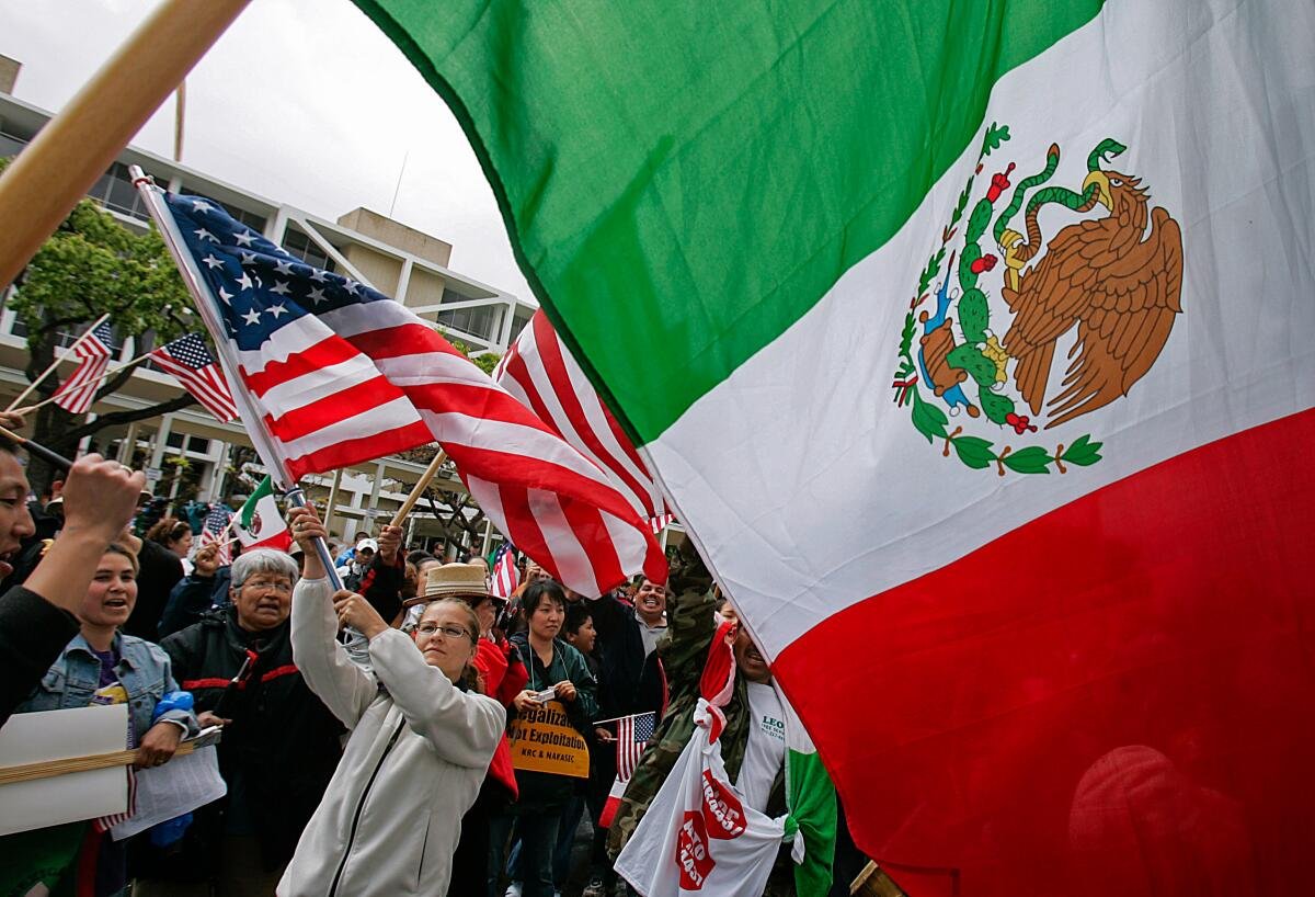 Demonstrators wave Mexican and American flags in Costa Mesa