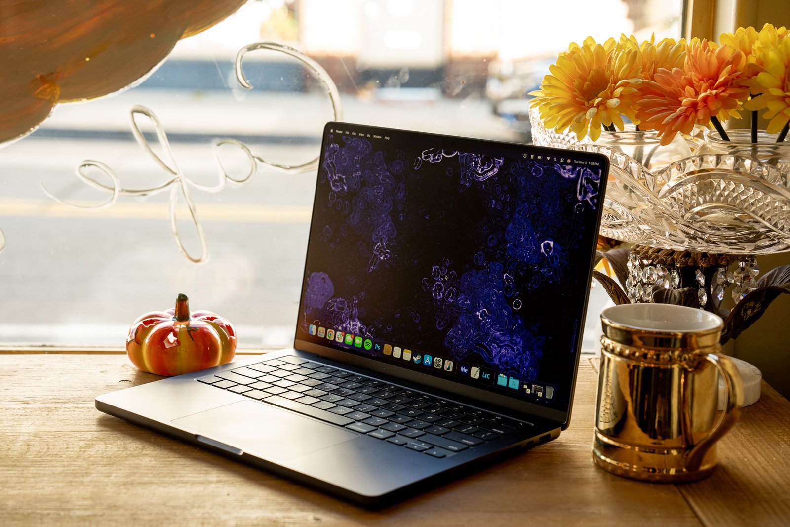 A 14-inch MacBook Pro M4 laptop on a wooden cafe counter near a window.