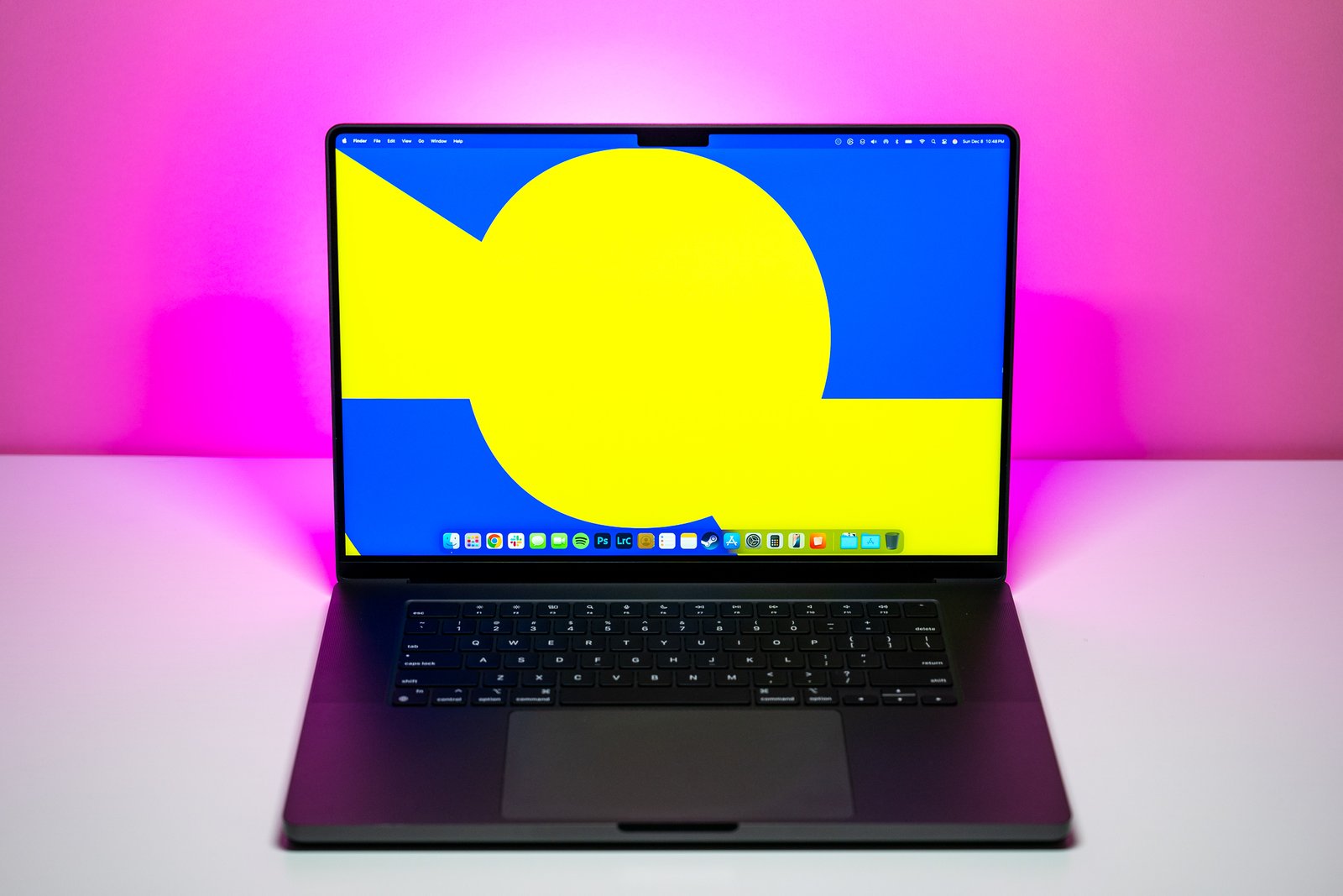 The 16-inch MacBook Pro with M4 Max chip on a white table with pink background.