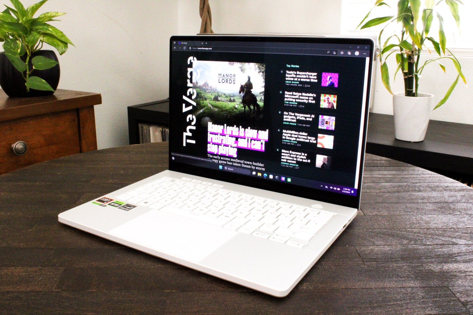 An open and powered on laptop sitting on top of a dark wood table.