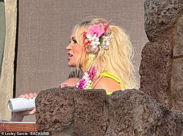 The blonde beauty had flowers tucked behind one ear as she waved to fans and onlookers during the outdoor shoot