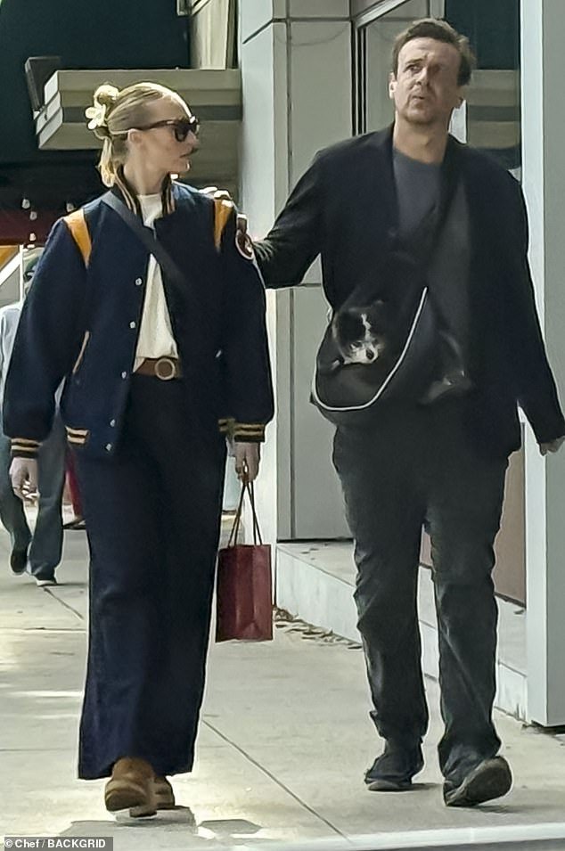 Jason Segel touches his girlfriend Kayla Radomski’s shoulder as he carries his dog in a crossbody purse