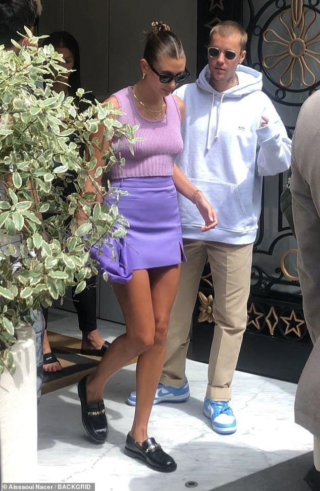 Hailey, 28, showed off her model's form, displaying her toned legs and arms in a sleeveless lavender vest and a violet mini skirt. The Rhode Beauty founder wore a pair of black loafers and styled her dark blonde locks in a high, sleek bun