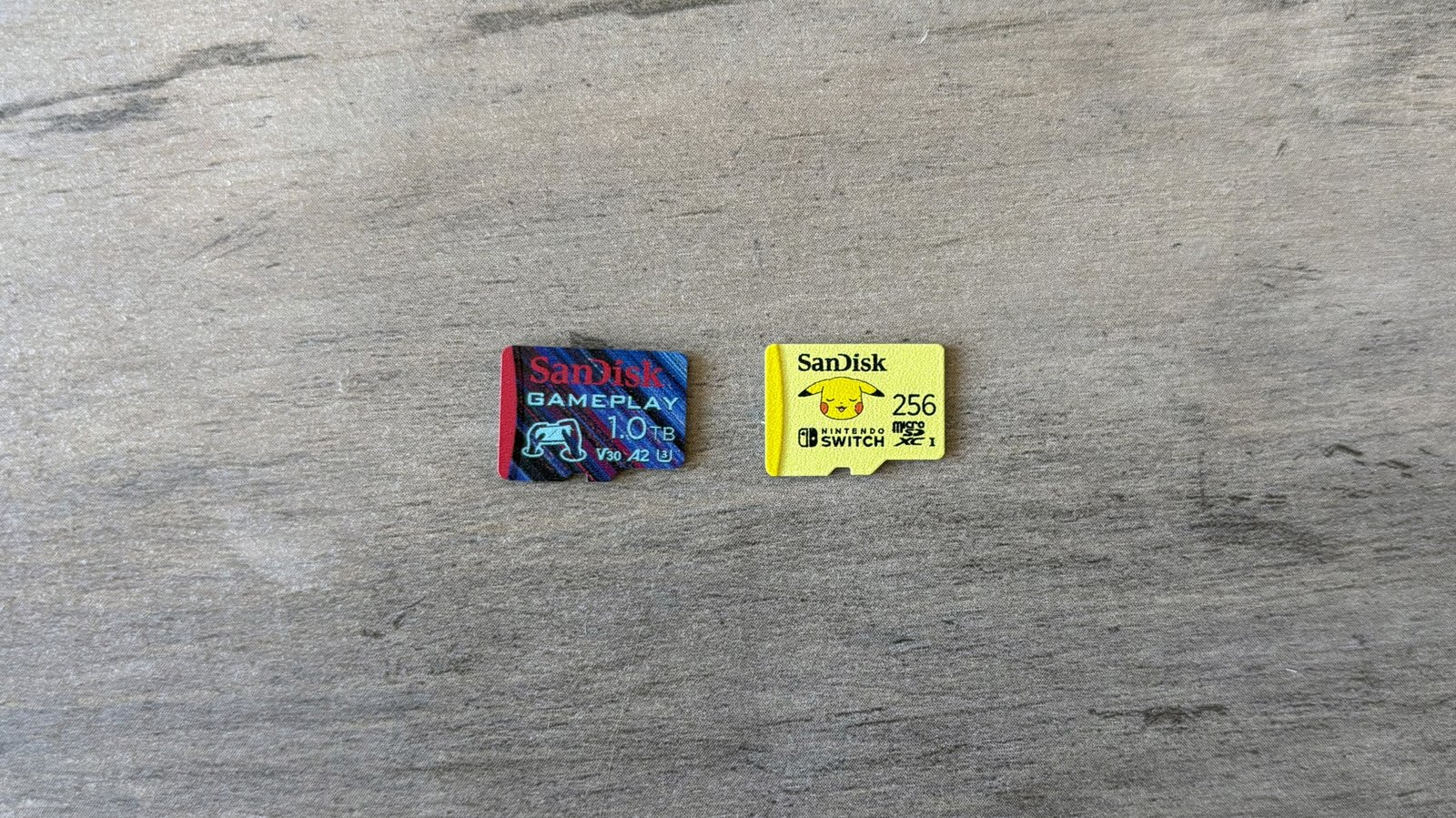 The SanDisk GamePlay and SanDisk Pokémon microSD cards rest on a brown wooden table.