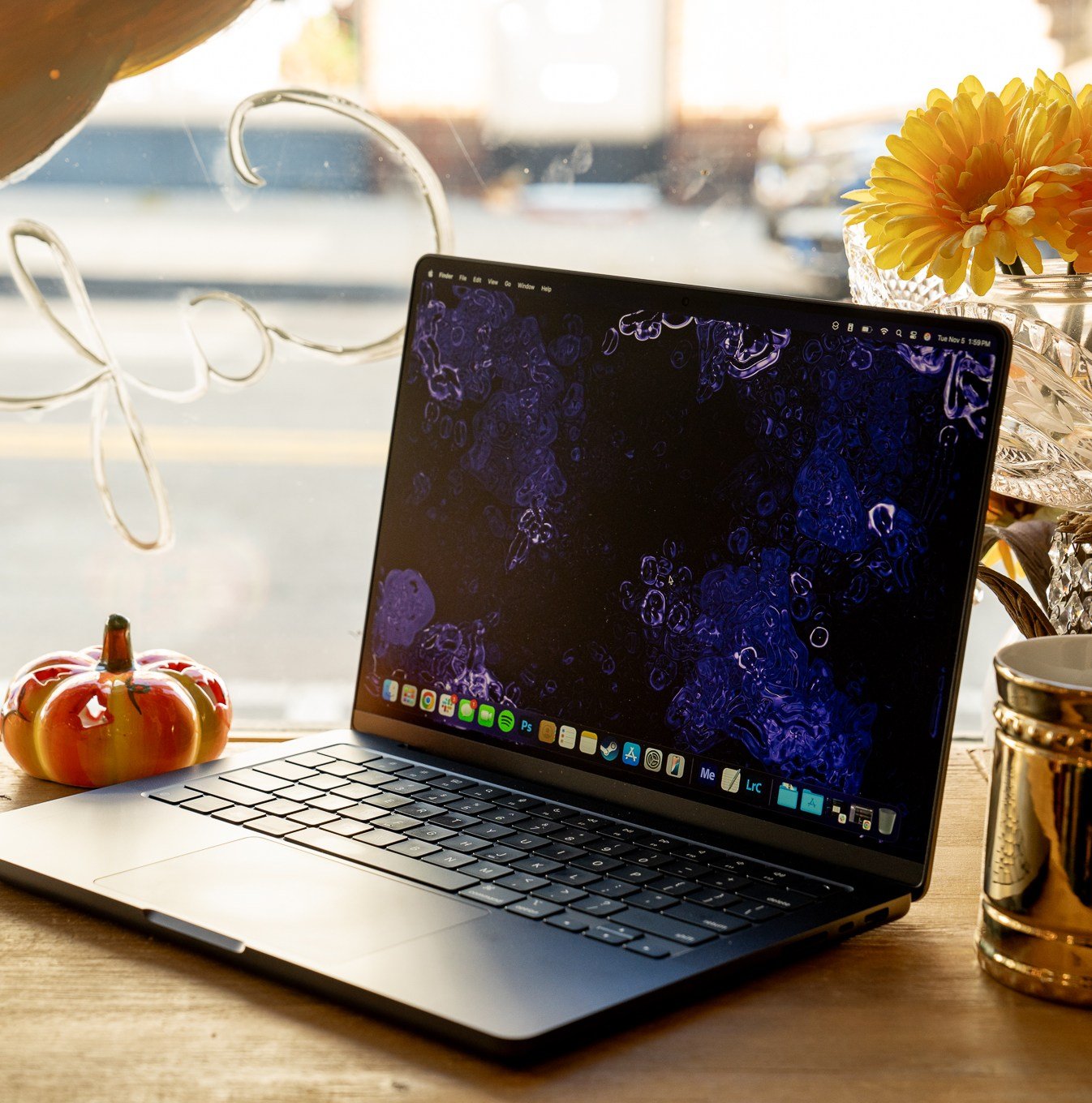 A 14-inch MacBook Pro M4 laptop on a wooden cafe counter near a window.