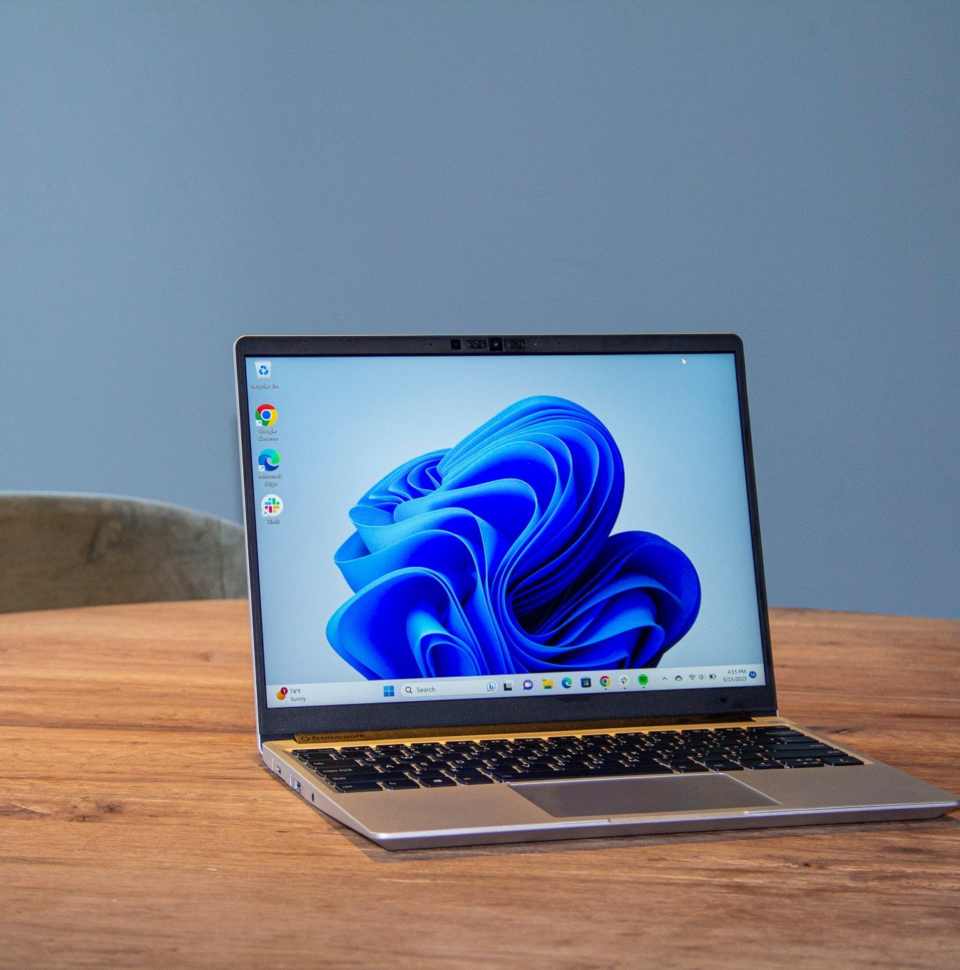 Best Laptop 2023: The Framework Laptop on a wooden table displaying a blue desktop background.